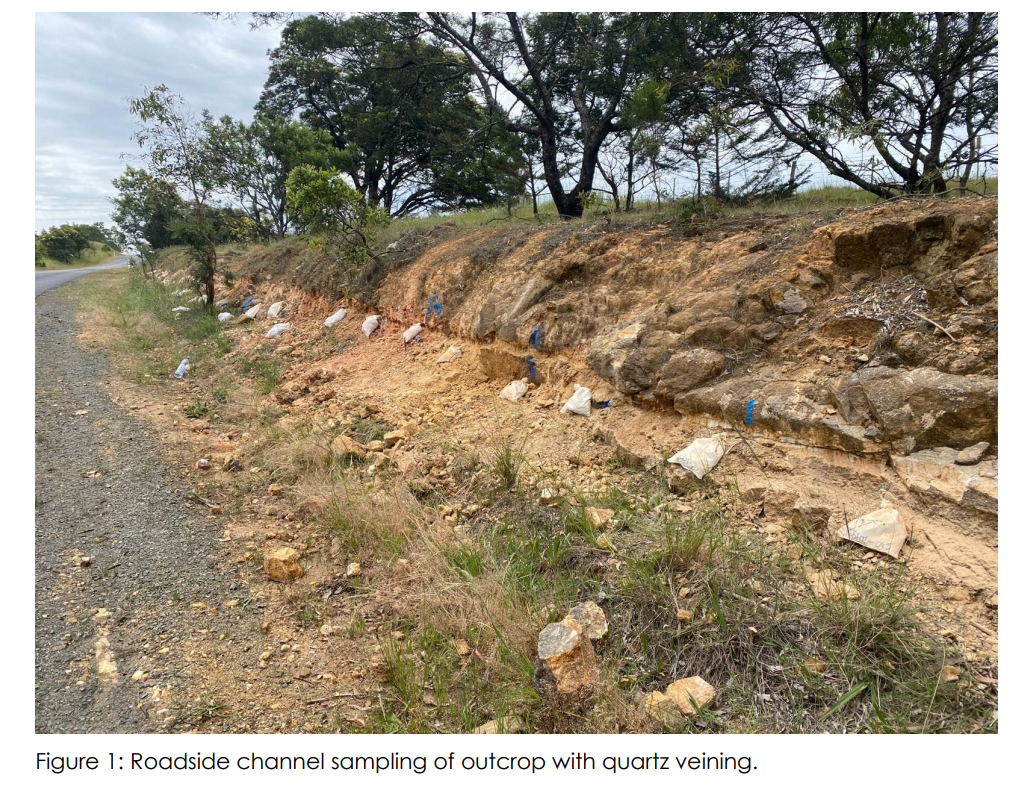 Roadside rock outcrop with visible quartz veining and marked channel sampling points along a shallow roadside cutting