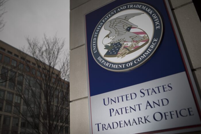 Sign outside the United States Patent and Trademark Office building featuring the USPTO seal and Department of Commerce branding.