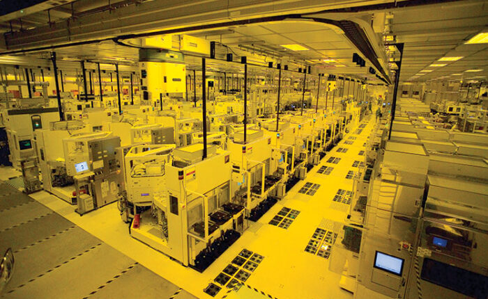 Semiconductor fabrication cleanroom with rows of advanced chip manufacturing equipment inside a large wafer production facility.