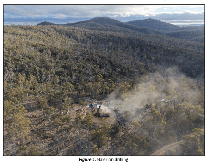 Aerial view of a drill rig operating in a cleared forest site at Balerion Prospect, surrounded by rolling bushland hills.
