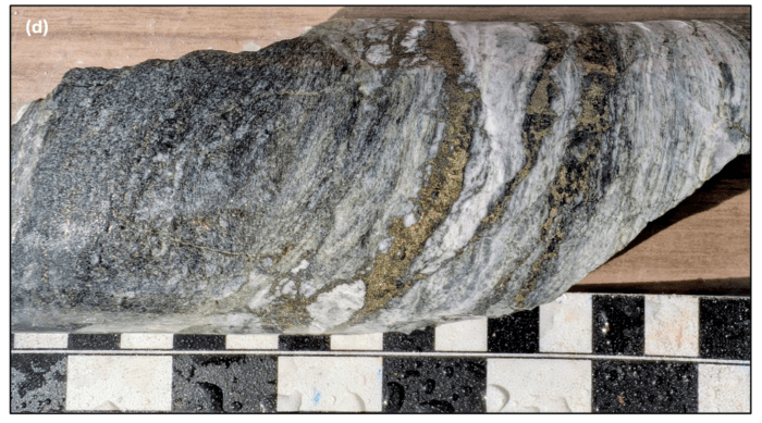 Close-up of drill core showing folded quartz veining with visible sulphide mineralisation and metallic grains.