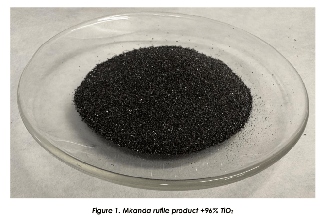 Glass dish containing a mound of black rutile concentrate, labelled as Mkanda product grading more than 96% TiO₂.