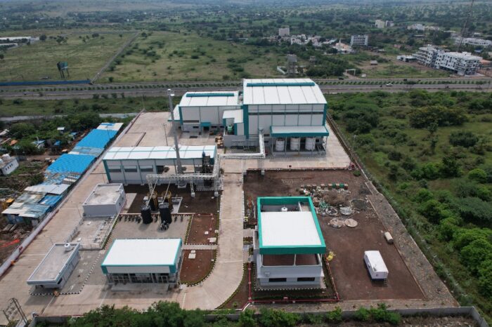 Aerial view of a large industrial graphite processing facility with multiple buildings, storage tanks and internal roads.