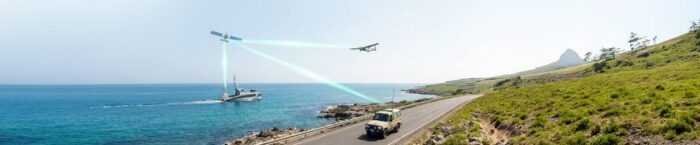 Drone and boat conduct coastal survey with green laser mapping beams along an ocean road.