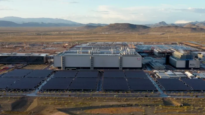 Aerial view of a large semiconductor manufacturing facility surrounded by desert landscape and mountains.