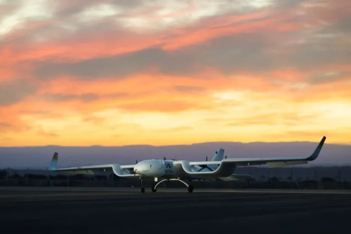 Vestal unmanned aircraft on a runway at sunset, silhouetted against orange and pink clouds and distant mountains.